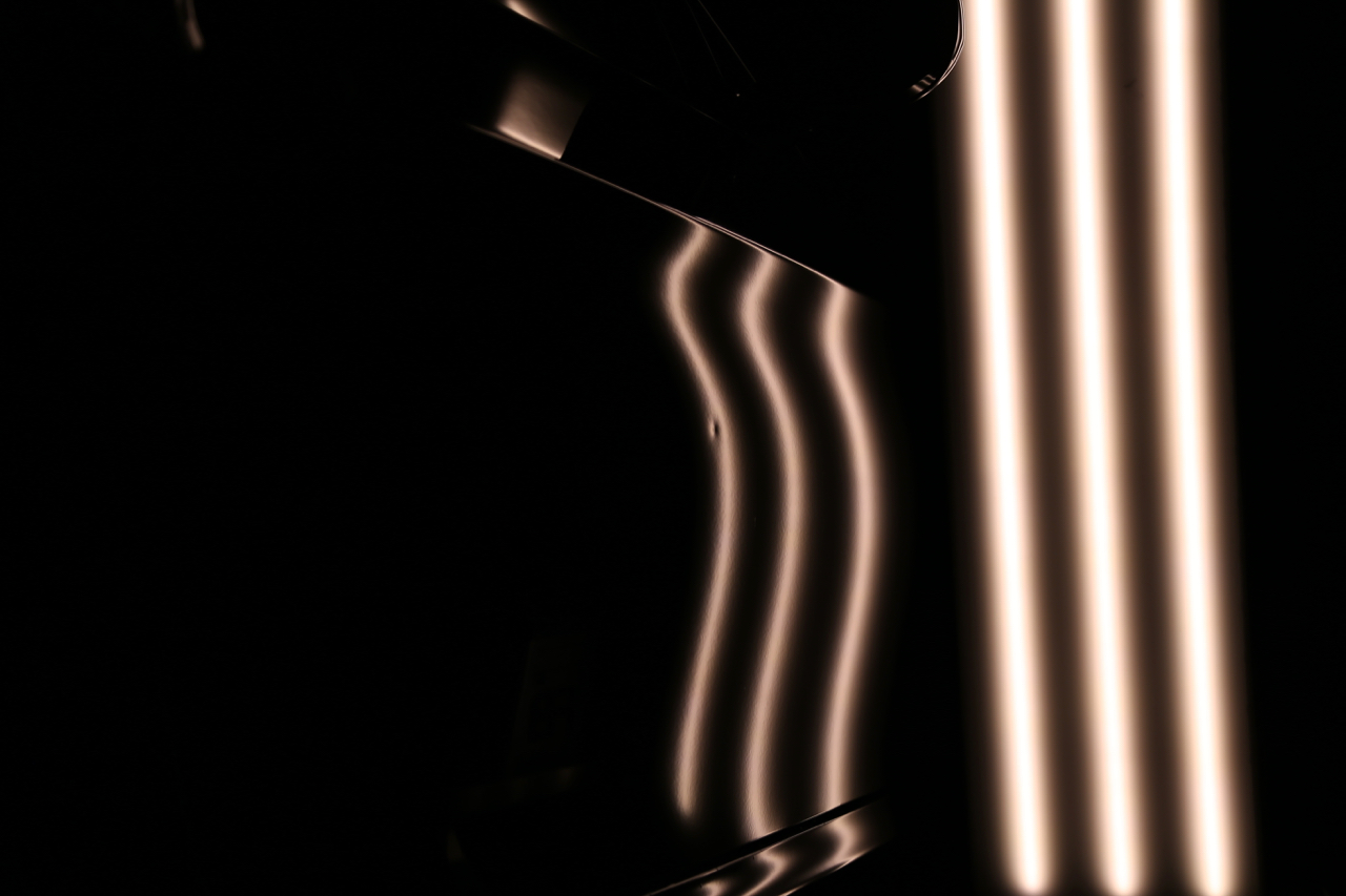 Paintless dent repair reflection lines showing panel damage at Dent X