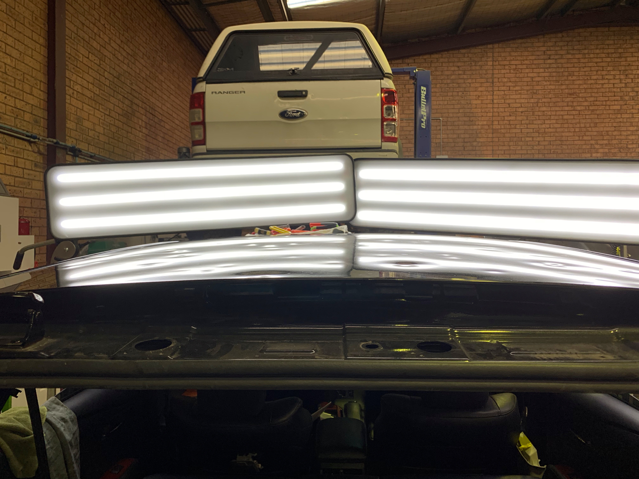 Before photo showing multiple dents in a dark vehicle roof panel