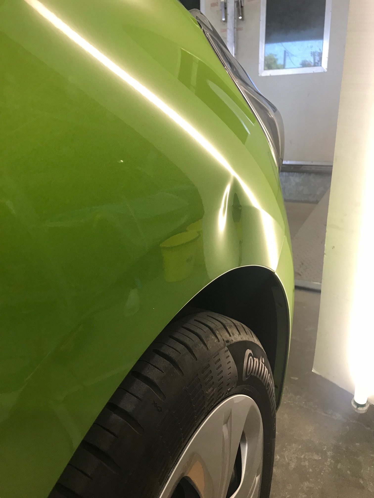 Dent X before photo showing a dent in a green vehicle front guard