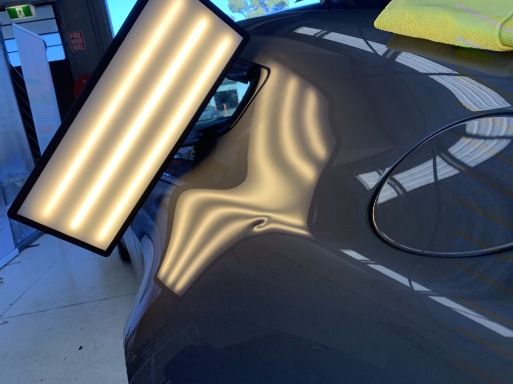 Before photo showing dent damage near a grey vehicle fuel door