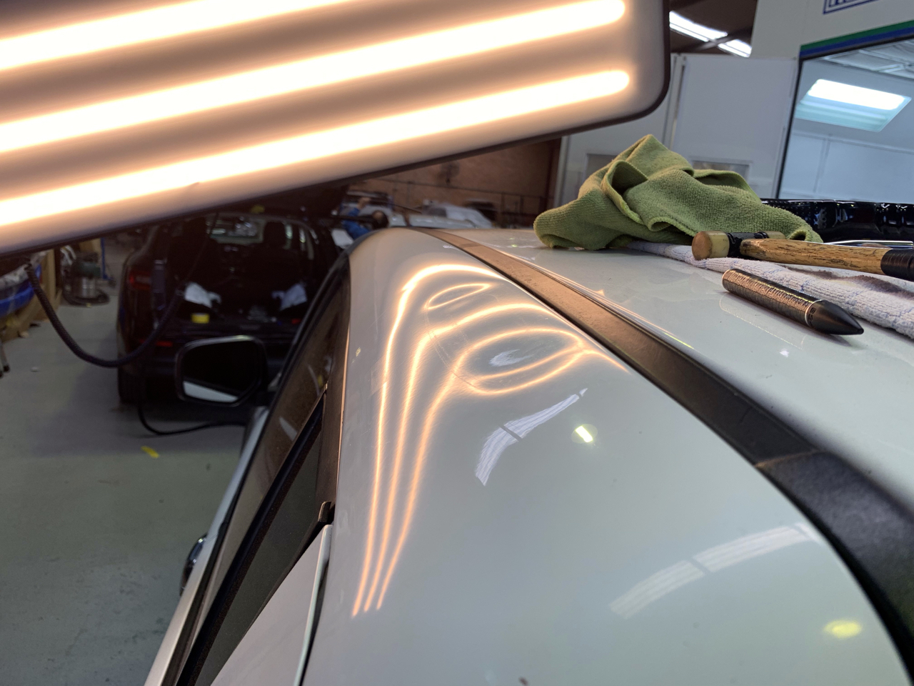 Before photo showing a dent near a white vehicle roof edge