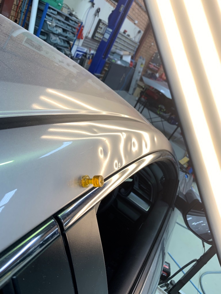 Before photo showing dent damage along the upper door and roof edge