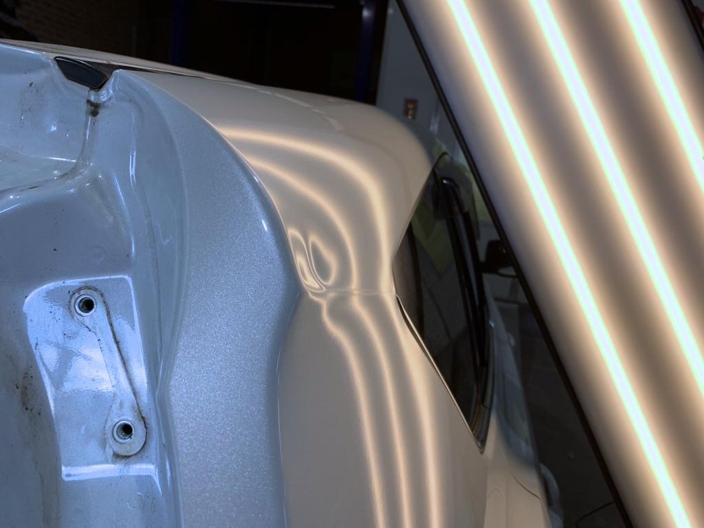 Before photo showing damage to a white upper body panel