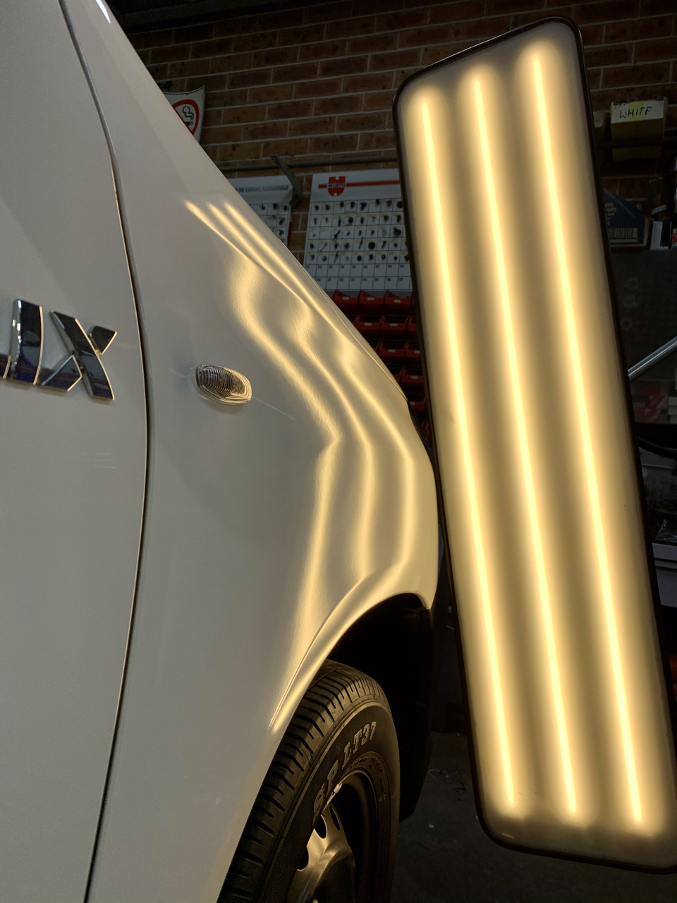 After paintless dent repair on the white vehicle front guard at Dent X